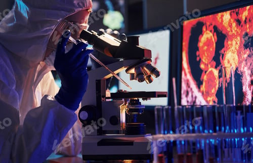 Preview: Scientist in white protective uniform near displays with data works with coronavirus and blood tubes