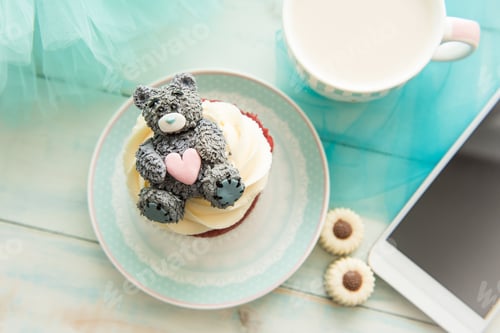 Preview: Cupcake, mug, phone, sugar Teddy, chocolates and a notebook on turquoise background