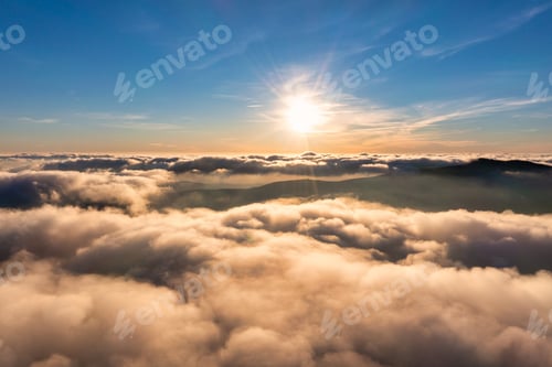 Preview: Sun shining above layer of white fluffy clouds at sunset