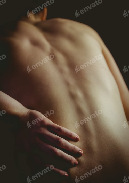 Preview: Nude woman with a back injury on black background