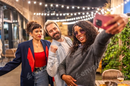 Preview: Latin woman taking selfie with friends at night party outdoors