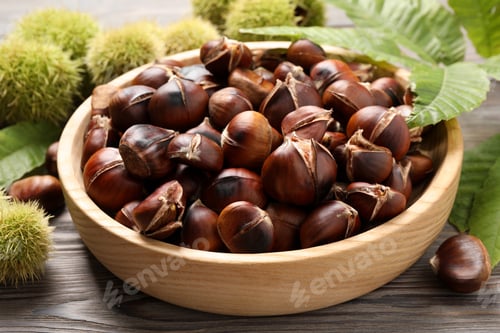 Preview: Delicious roasted edible chestnuts in wooden bowl on table, closeup