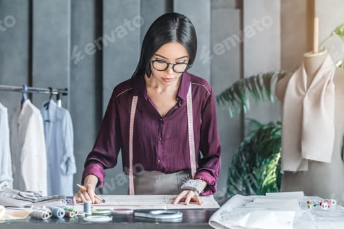 Preview: Asian woman fashion designer working on her model in showroom
