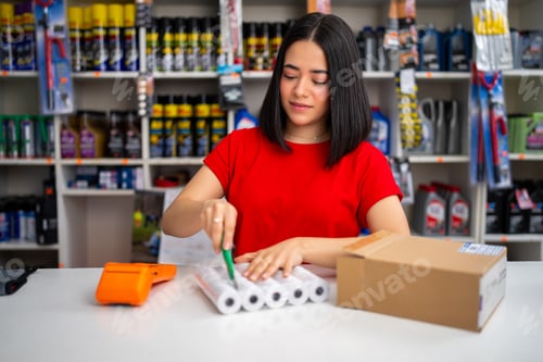 Preview: Woman worker preparing products for online order delivery in an auto parts shop