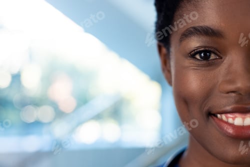 Preview: Half face portrait of smiling african american female doctor in hospital corridor with copy space