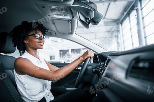 Preview: Young african american woman sits inside of new modern car