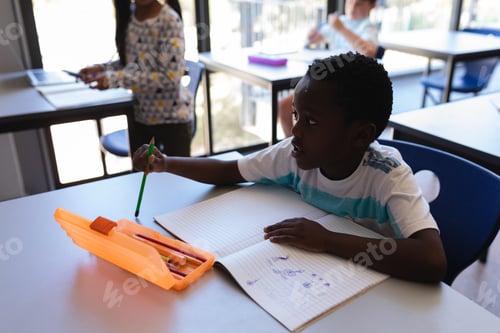 Visualização: Vista lateral do estudante sentado na mesa e olhando para o outro lado na sala de aula do ensino fundamental