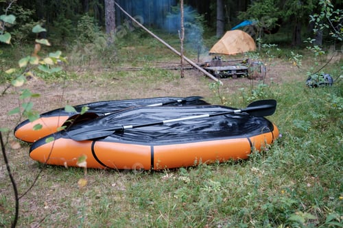 Preview: Two packrafts lie to dry in the camp, against the backdrop of a tent, in the forest, in summer.