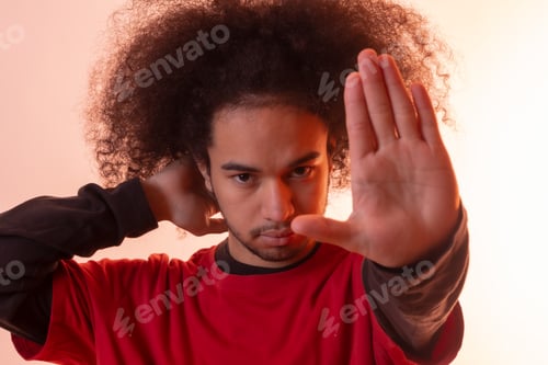 Preview: Portrait with a red led light with a stop gesture. Young man with afro hair on white background