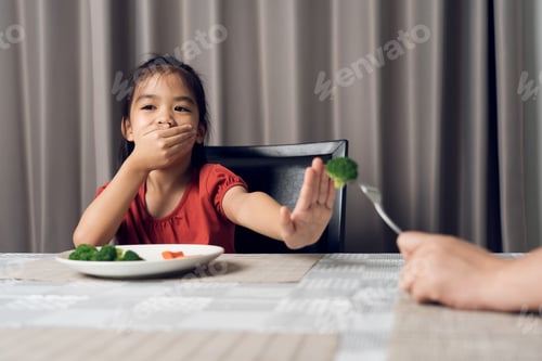 Preview: Little cute kid girl refusing to eat healthy vegetables. Children do not like to eat vegetables.