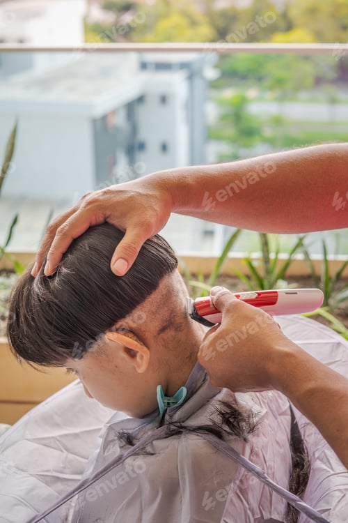 Preview: Asian child getting a haircut at home from the father.