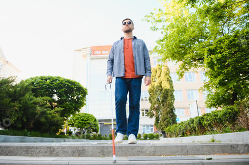 Preview: Young handsome blinded man walking with stick in town