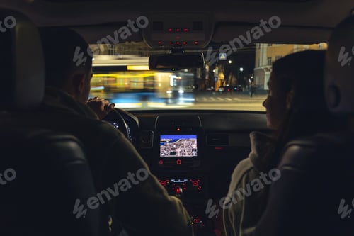 Preview: Man and woman in a car at night, view from the car.