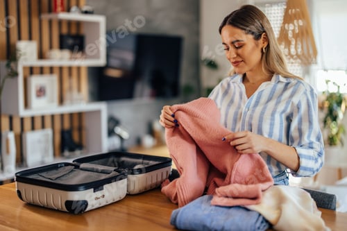 Preview: Woman Packing Clothes Into a Suitcase for Travel in a Modern Interior