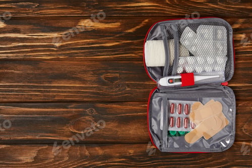 Preview: top view of opened first aid kit bag on wooden tabletop