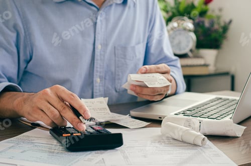 Aperçu: Businessman using calculator and calculating bills in office at home