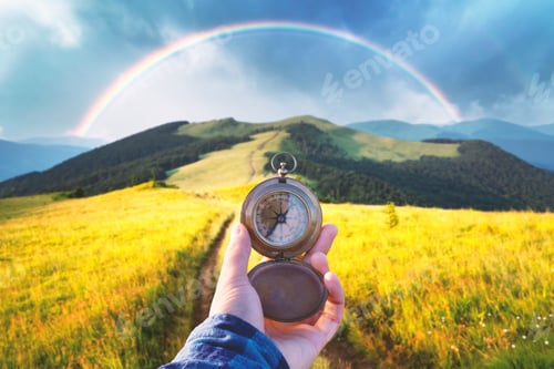Preview: Man with old metal compass in hand on mountains road