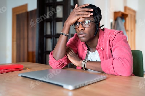 Preview: Depressed sad young African student guy feeling lazy and unmotivated to study online