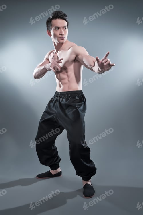 Preview: Muscled Asian Kung Fu Man In Action Pose. Blood Stripes On His Chest. Wearing Black Pants. Studio