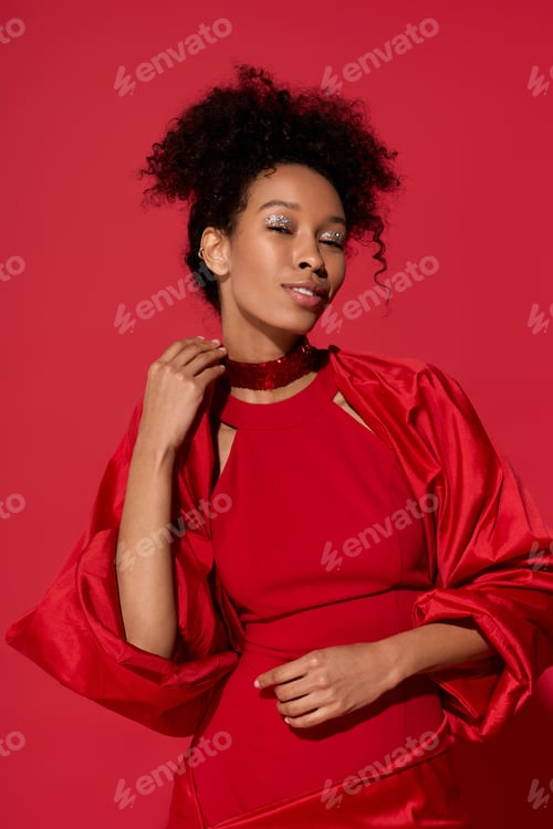 Preview: Young beautiful woman in vibrant red attire posing confidently against a bold red background
