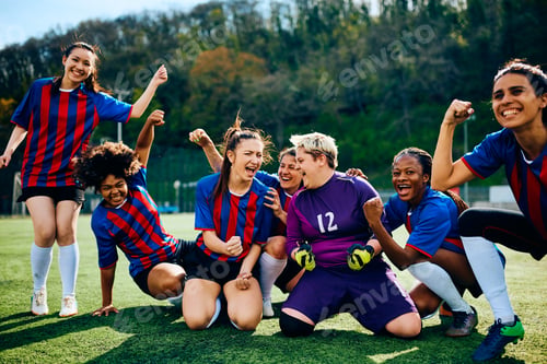 Preview: Excited female players celebrating after winning soccer match at the stadium.