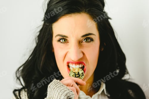 Preview: Aggressive woman biting a golden bitcoin coin isolated on white.