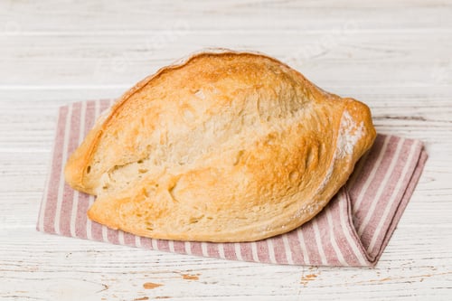 Preview: freshly baked bread with napkin on rustic table top view. Healthy white bread loaf isolated