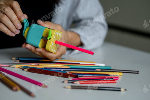 Preview: The girls' hands hold a sharpener and colored pencils. The process of sharpening pencils