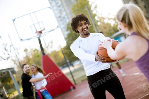 Preview: Multiracial couple playing basketball on outdoor court