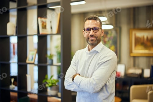 Preview: Portrait of a businessman posing for the camera with his hands crossed, at the office.