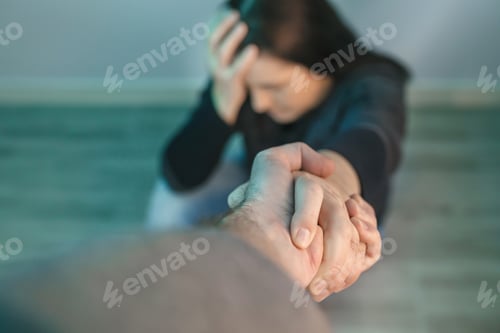 Preview: Unrecognizable woman with mental health problems receiving help from man holding her hand