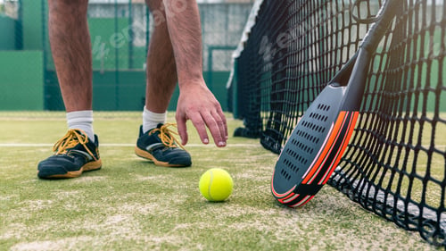 Preview: One caucasian man catch a yellow ball near the padel racket on green court grass