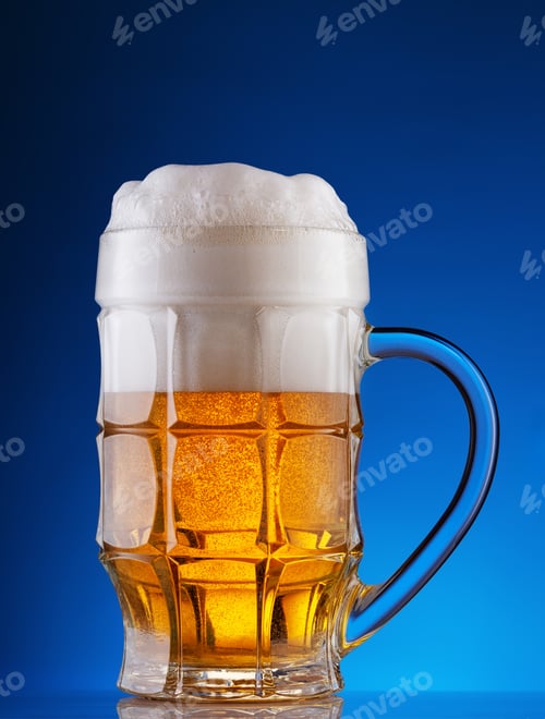 Preview: Faceted mug of light beer with foam on blue background