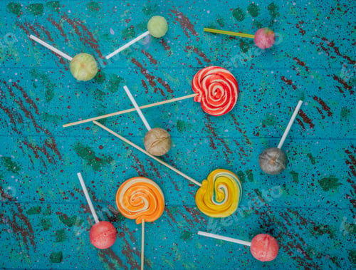 Preview: top view of colorful lollipop candies scattered on blue background