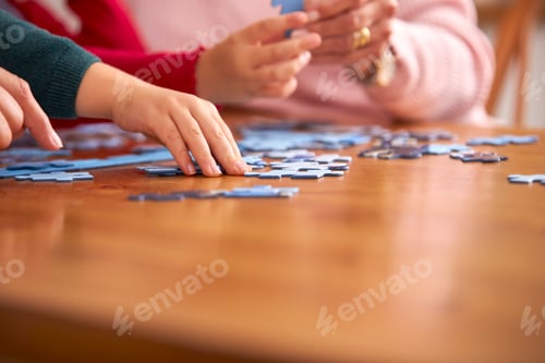 Preview: Close Up Of Grandchildren With Grandparents Sit Around Table At Home Doing Jigsaw Puzzle Together