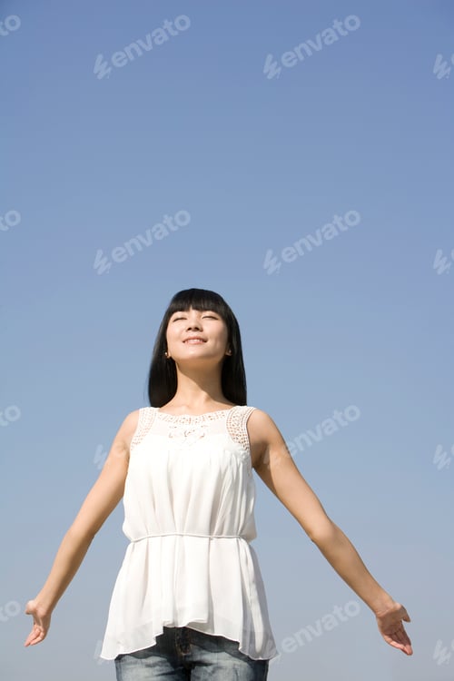 Preview: Young woman standing outdoors, arms out-stretched