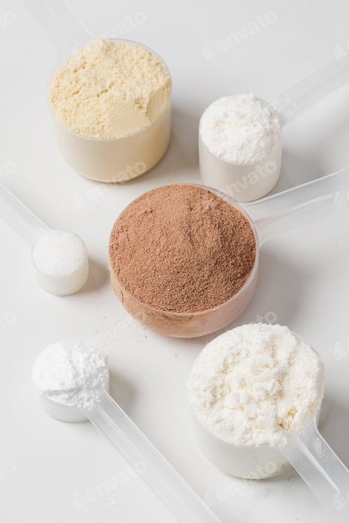 Preview: Assorted protein powder and supplement scoops on white marble background for nutrition and fitness
