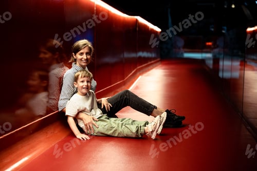 Preview: Woman and Little Boy Share Genuine Smiles Against Red Background, Radiant Joy.