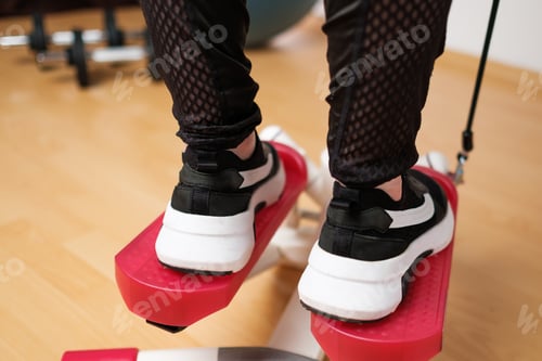 Preview: Back view on the woman feet in sneakers doing exercising on the twist stepper or stair stepper