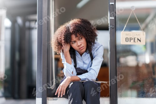 Preview: Female shopkeeper sitting stressed out at the store entrance frustrated by the economic impact.