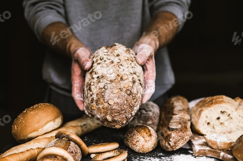 Preview: Baker man holding a rustic organic loaf of bread in his hands