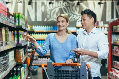 Preview: A young international couple, a woman and an Asian man walk with a shopping cart in a supermarket