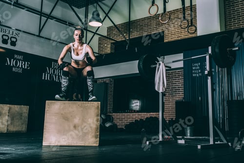 Preview: Fit blonde woman jumping box training working out in Gym