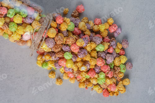 Preview: A jar of colorful popcorn candy spilled over on marble background
