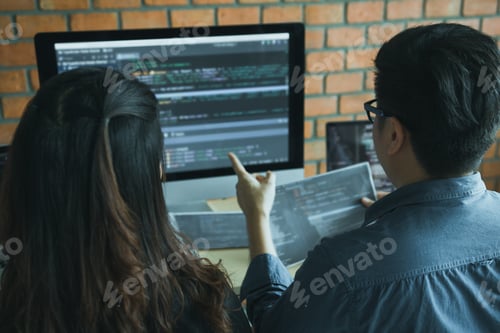 Preview: Two software developers are using computers to work together with their partner at the office desk.