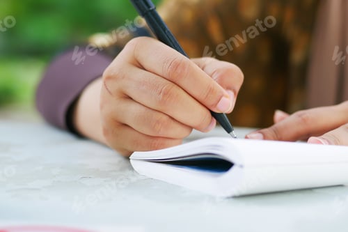Preview: Close up of women hand writing on notepad.