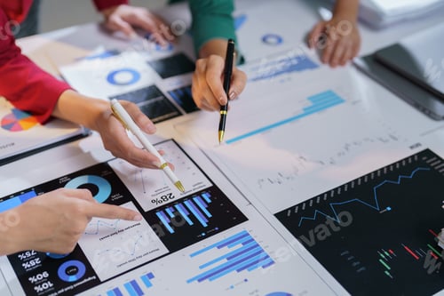 Preview: Business team members are pointing at financial charts and graphs, discussing company performance an