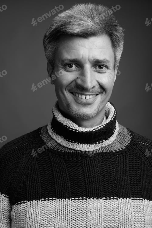 Preview: Man with blond hair wearing turtleneck sweater against gray background
