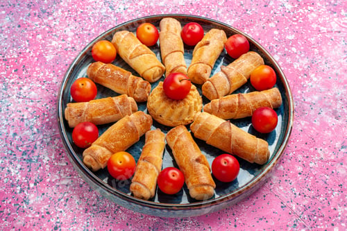 Preview: front view sweet delicious bagels baked pastries inside tray with plums on pink desk pastry cake