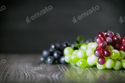 Preview: Colorful grape on wooden board dark background copy space